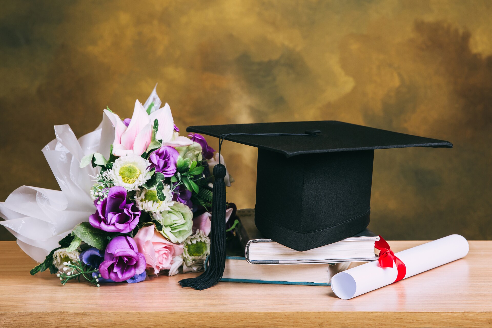graduation-cap-hat-with-degree-paper-flower-bouquet-wood-table.jpg